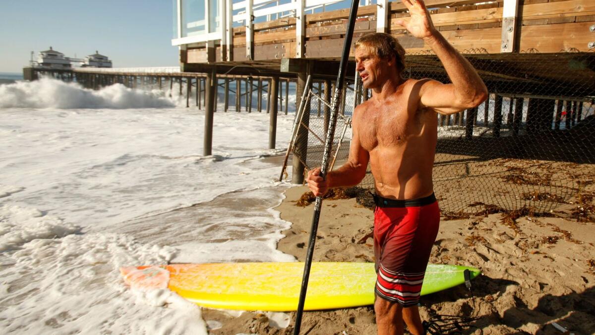 Renowned surfer Laird Hamilton prepares his standup paddle board in Malibu in this 2014 file photo. (Al Seib / Los Angeles Times)