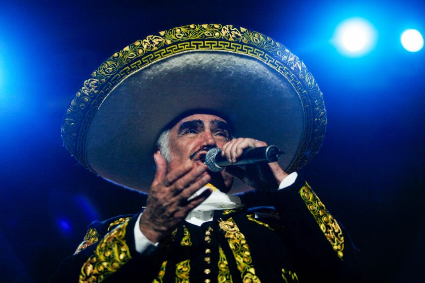 A man in mariachi attire sings in concert