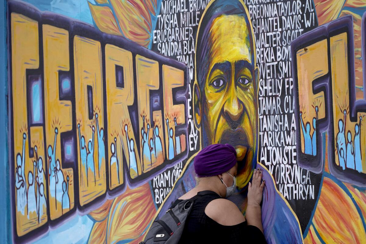 Paying her respects, a woman presses her head against a mural of George Floyd at George Floyd Square in Minneapolis