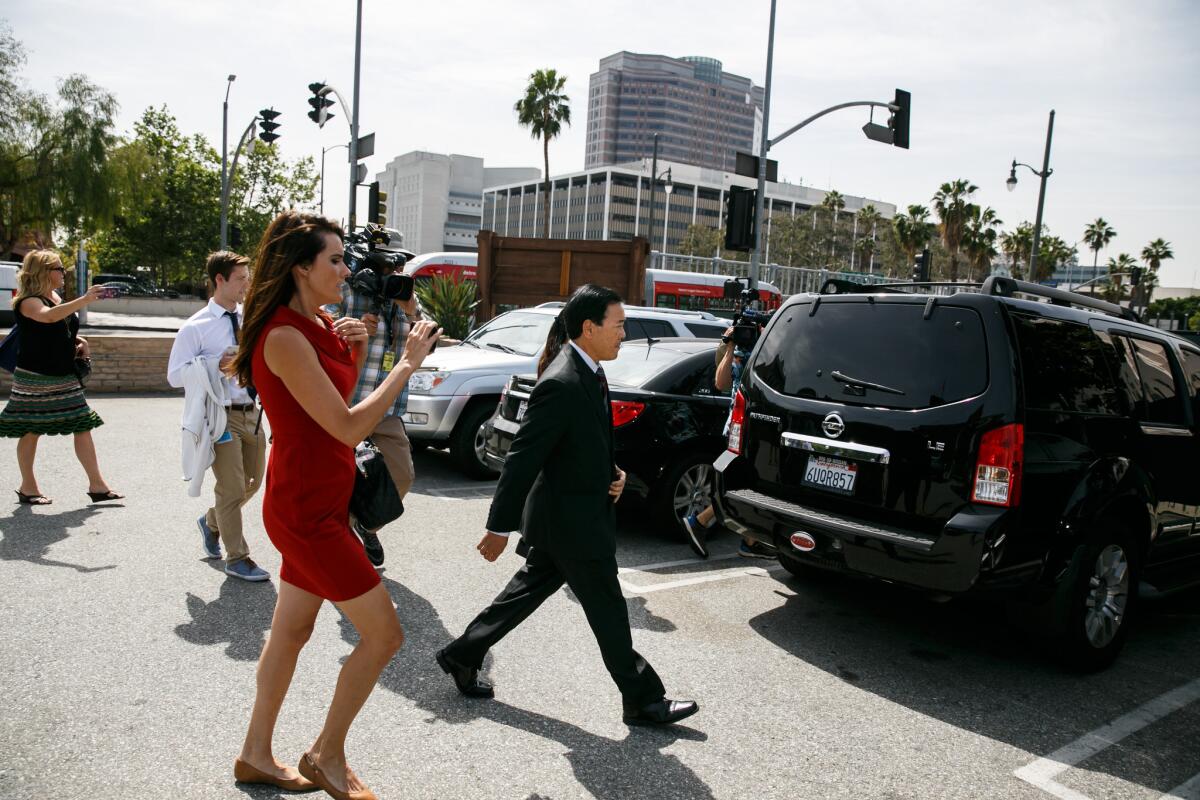 Former Los Angeles County Undersheriff Paul Tanaka, right, walks towards his car as members of the press follow.