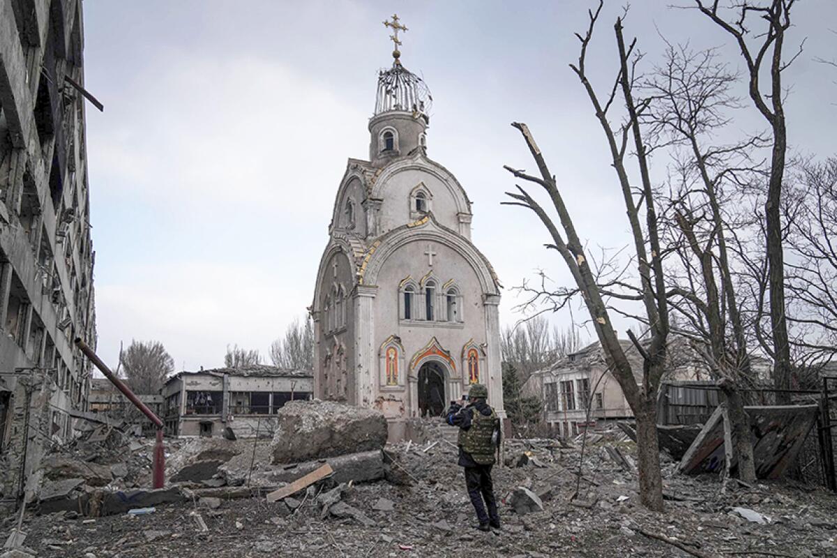 A Ukrainian serviceman takes photos of a demolished church in Mariupol, Ukraine 