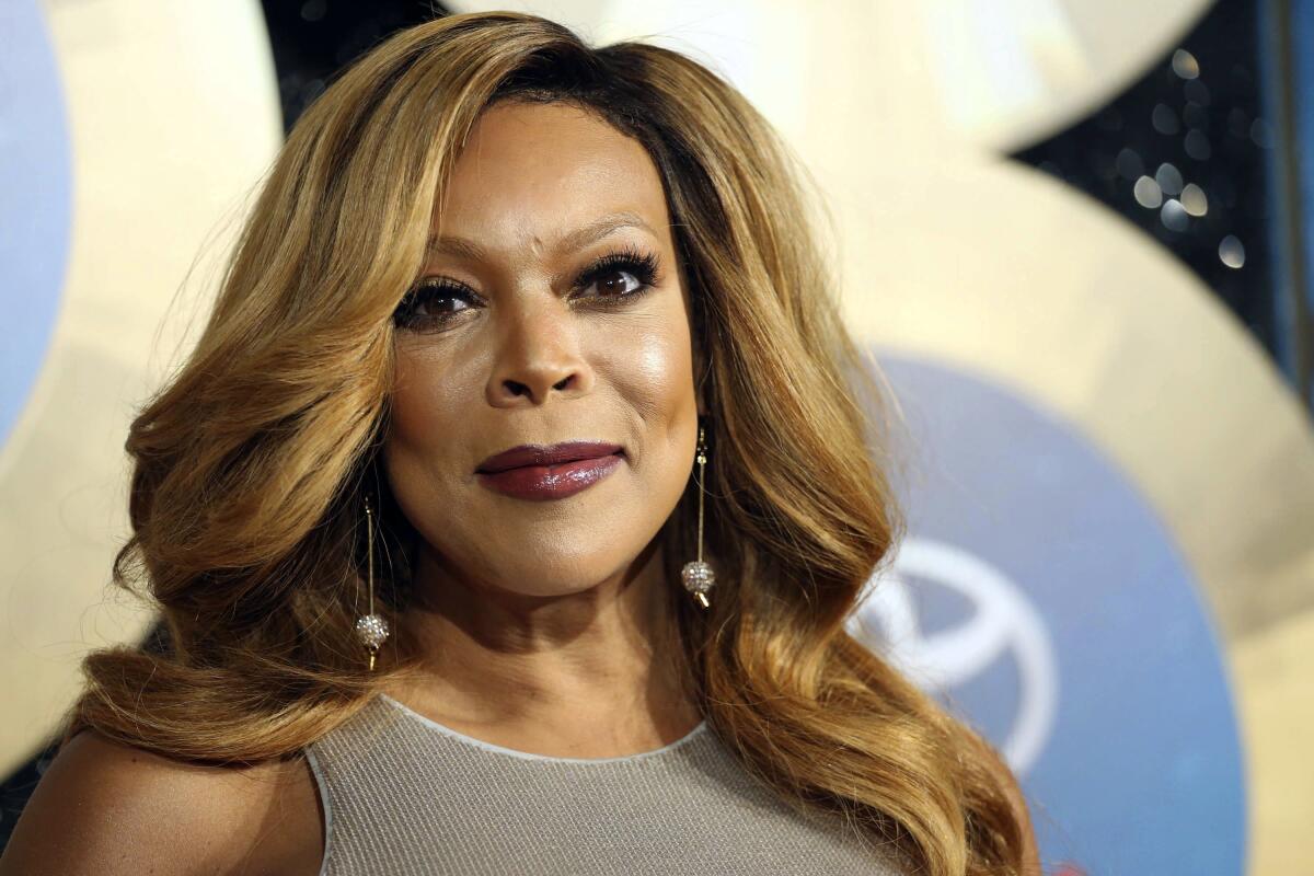 Wendy Williams in a gray sleeveless dress and drop pearl earring smiling