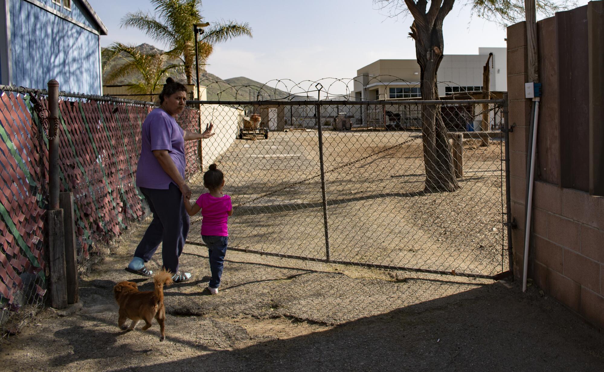 Jovita Diaz and 3-year-old Arianna head to the backyard, which has a view of a warehouse