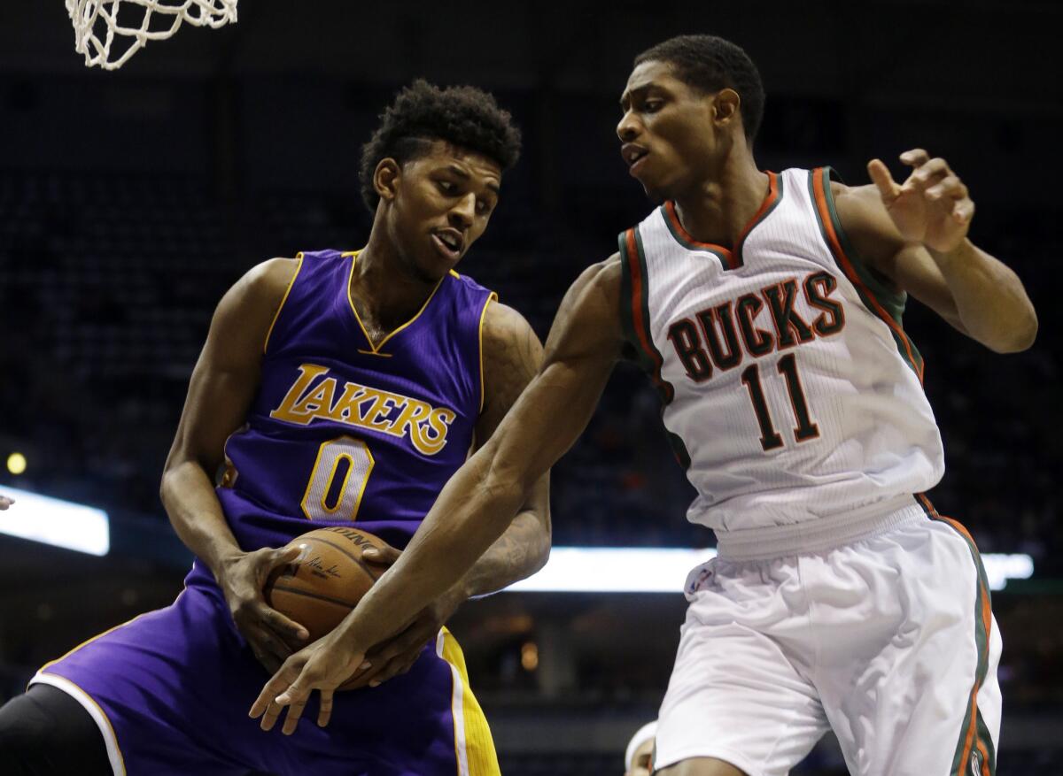 Nick Young grabs a rebound in front of Bucks guard Brandon Knight during the first half of the Lakers' 113-105 overtime loss Wednesday in Milwaukee.