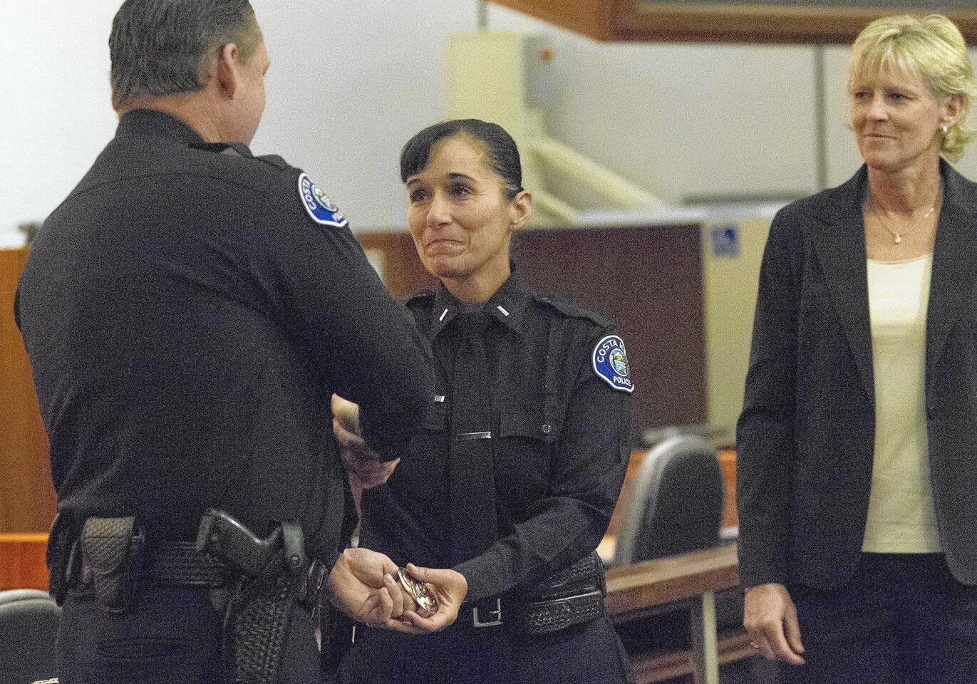 Joyce LaPointe, center, of the Costa Mesa Police Department, accompanied by her partner, Linzi Philips, right, accepts her new lieutenant badge from Police Chief Rob Sharpnack on Wednesday.