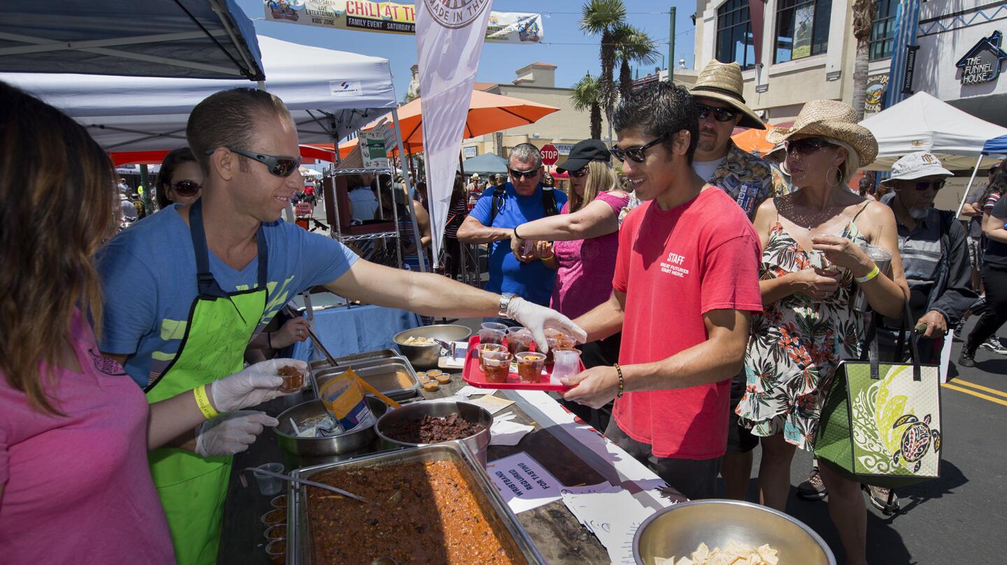 Chris Barnes, right, picks up chili samples from Justin Dahl, left, at Cruisers Pizza Bar Grill's booth for contest judges during the annual Chili at the Beach competition along Main Street in Huntington Beach on Saturday. (Kevin Chang/ Daily Pilot)