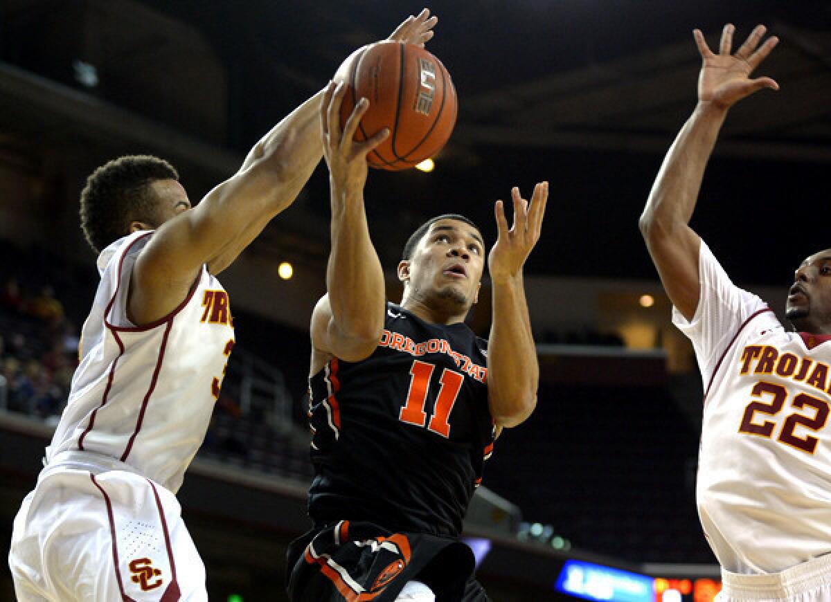 Oregon State guard Malcolm Duvivier (11) has his driving layup challenged by USC guards Chass Bryan and Byron Wesley (22) in the first half Thursday night at the Galen Center.