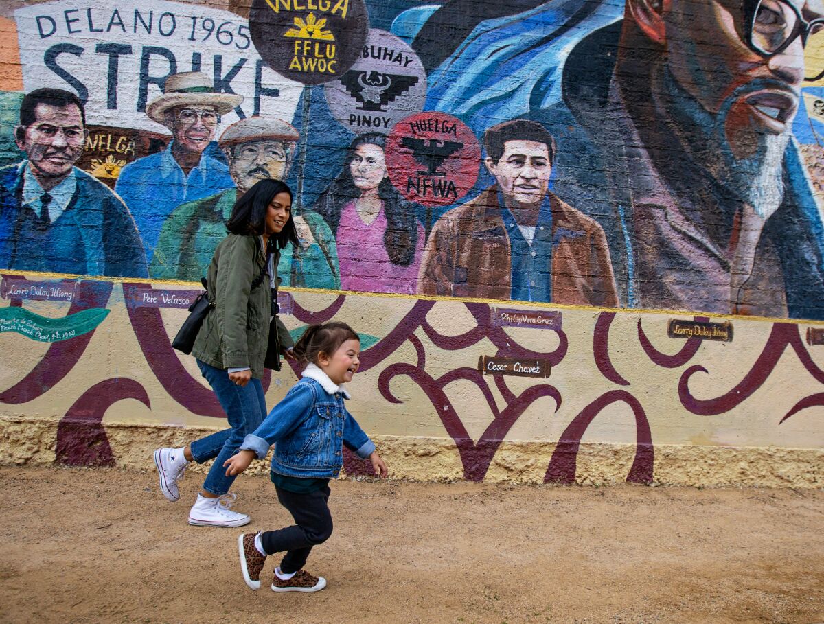 A woman and toddler in front of a mural.