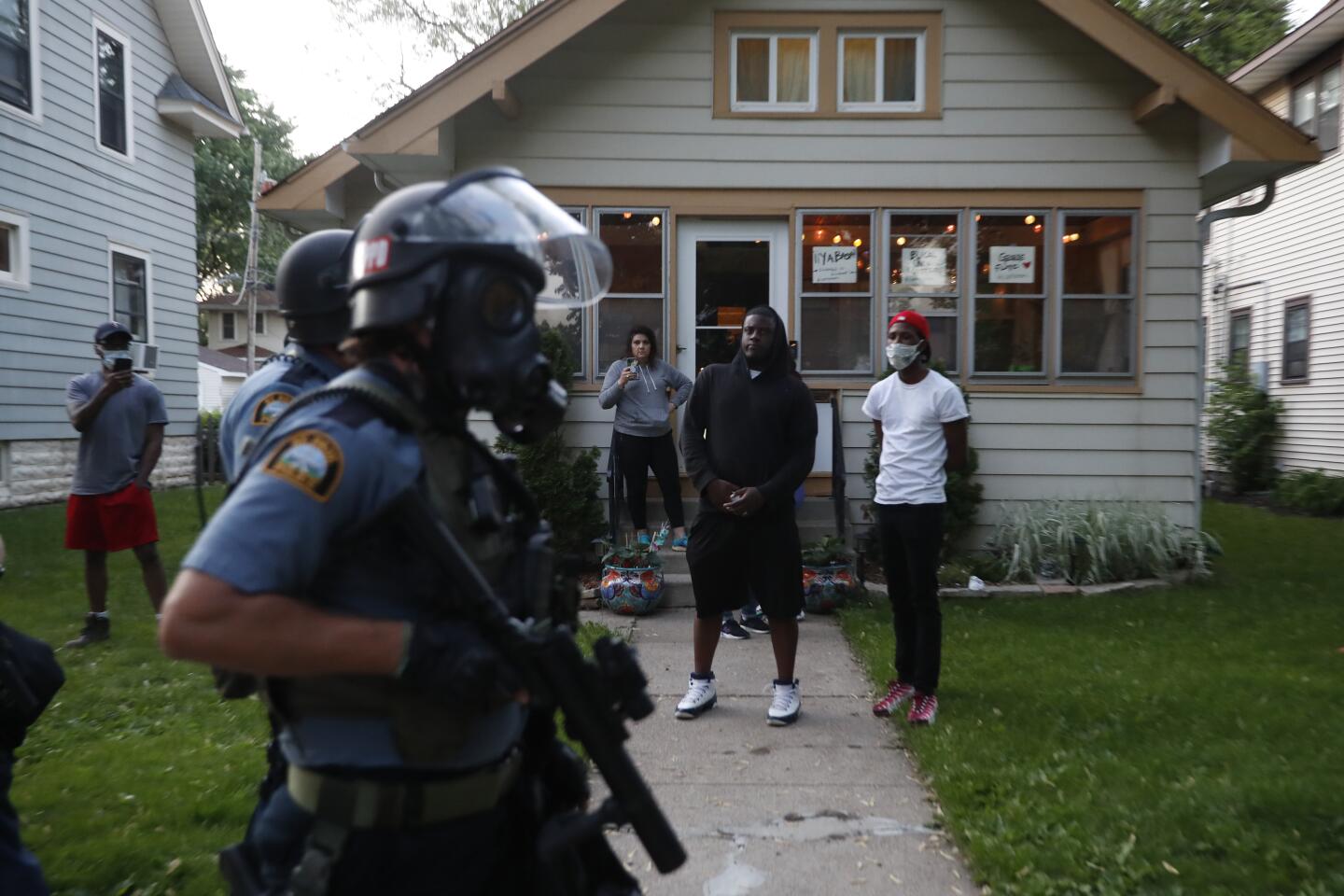 Bystanders watch as police walk down a street in St. Paul.