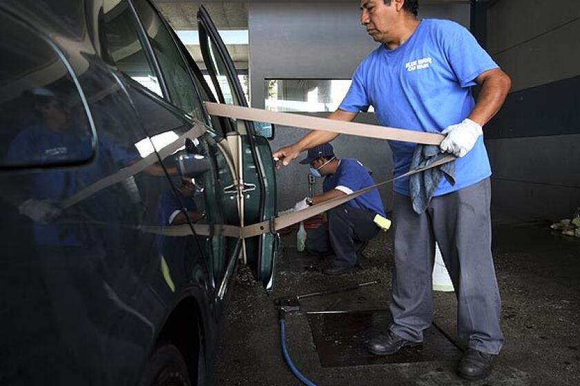 A worker at Blue Wave Car Wash in West Los Angeles washes a vehicle. A Times investigation has found that hand carwashes, automotive beauty shops patronized by tens of thousands of Southern California motorists every day, often brazenly violate basic labor and immigration laws, with little risk of penalty.