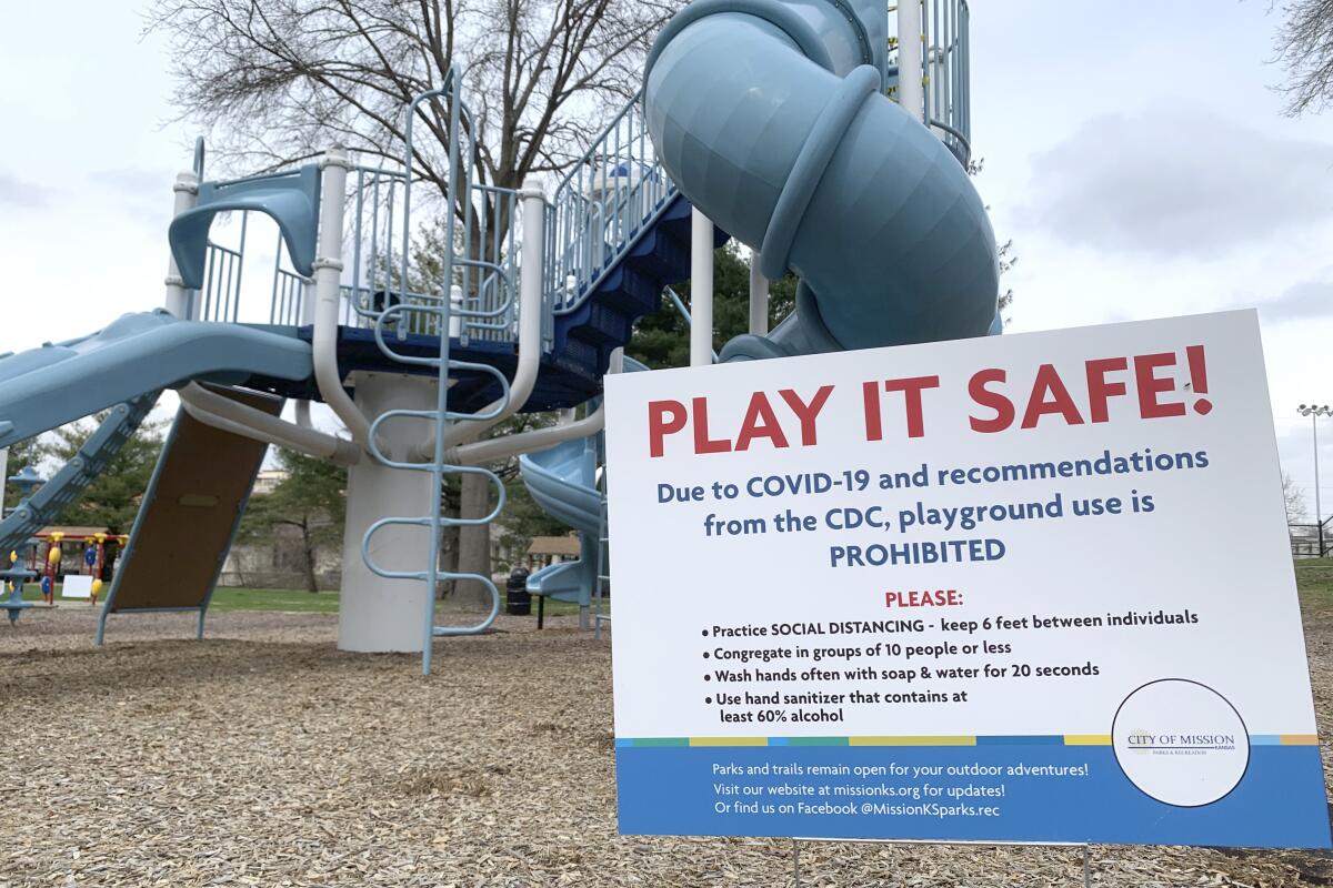 In this Thursday, March 26, 2020 photo, a sign posted at a Mission, Kansas playground, serves as a reminder to parents that use of the playground is prohibited, in compliance with social distancing guidelines. The new coronavirus causes mild or moderate symptoms for most people, but for some, especially older adults and people with existing health problems, it can cause more severe illness or death. (AP Photo/Heather Hollingsworth)