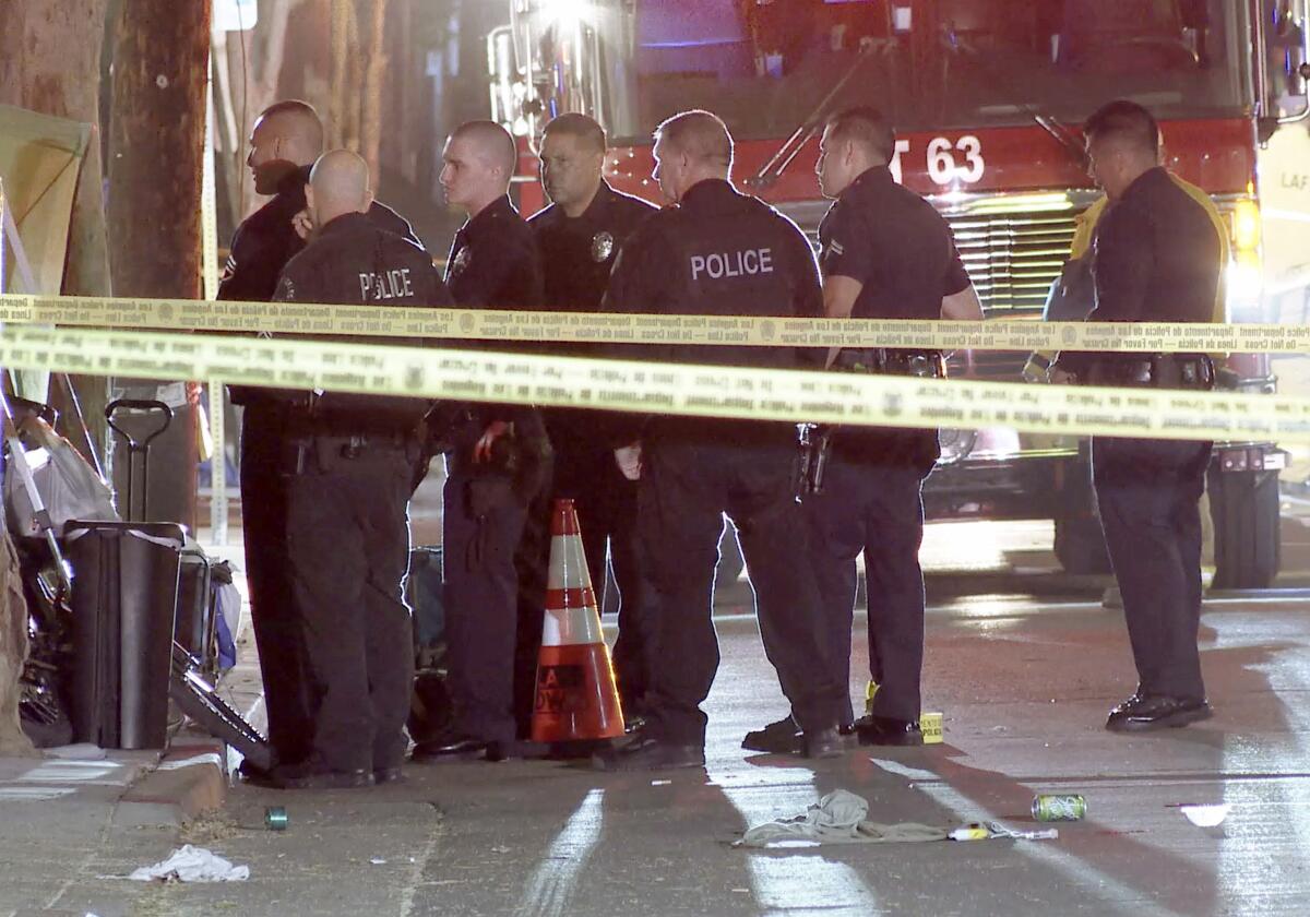 Police stand around the area behind yellow crime scene tape.