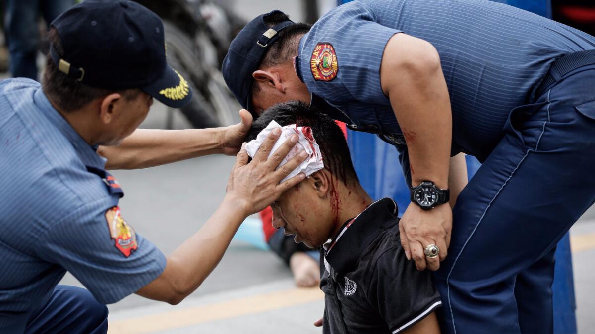 Police officers help an injured protester during a rally in front of the U.S. Embassy in Manila, Philippines. A police van rammed into protesters, injuring several.