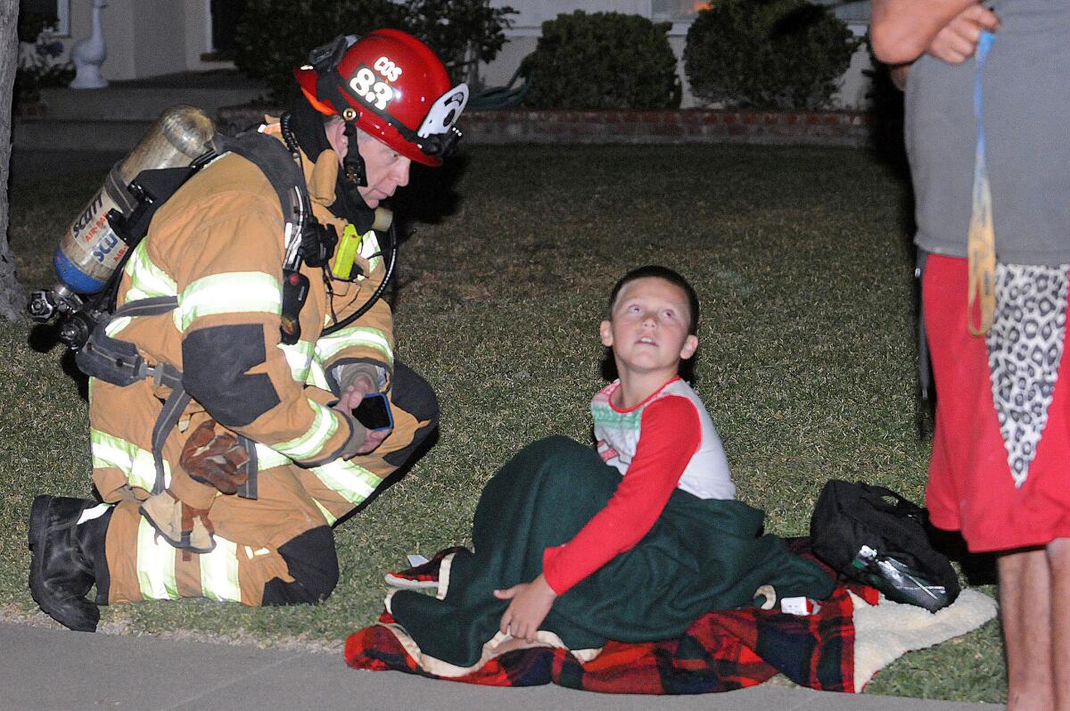 Costa Mesa fire Capt. Chris Coates speaks with 7-year-old William Rimmer, who alerted his father to a fire at their home.