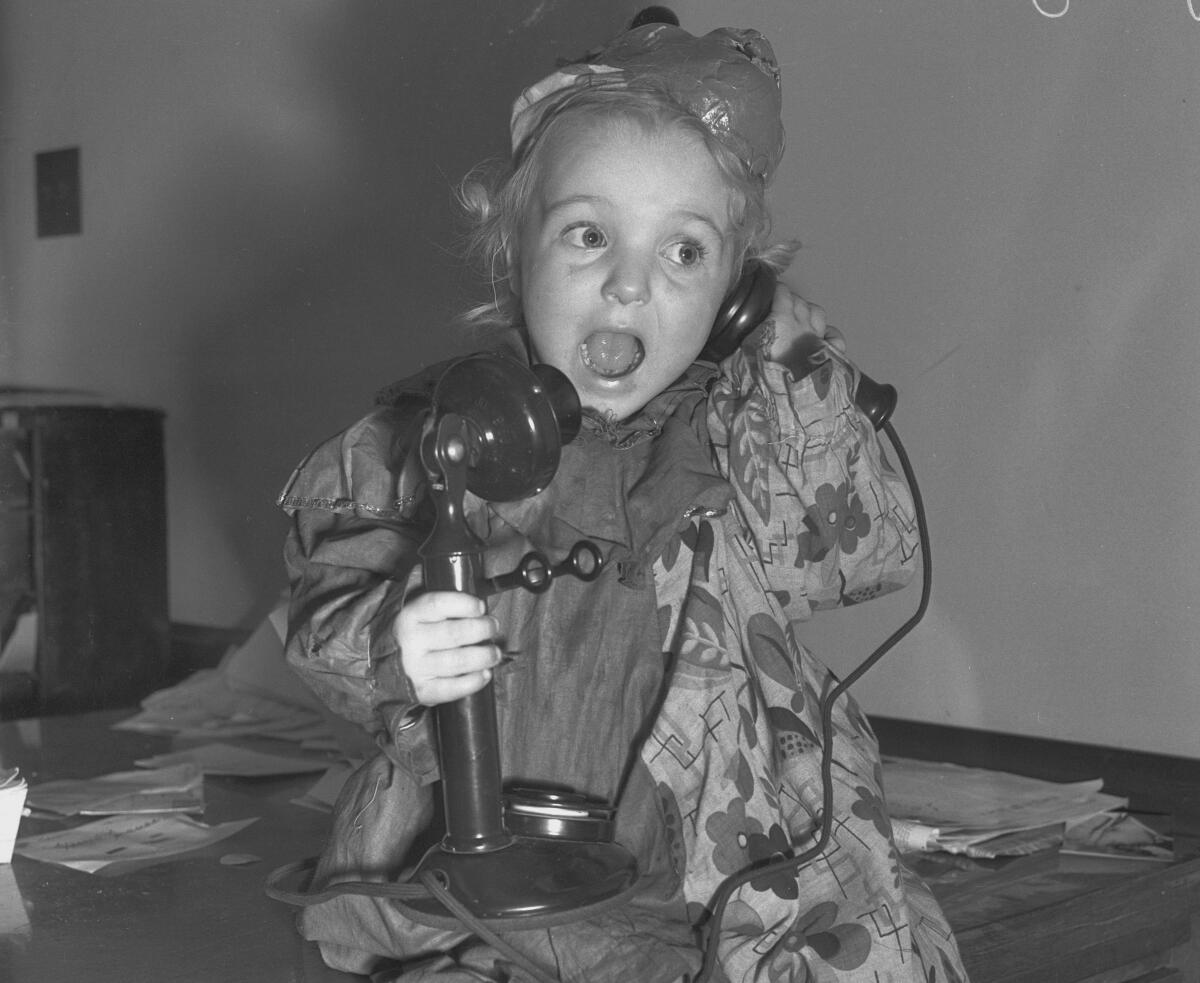 A child talks into an old fashioned telephone.