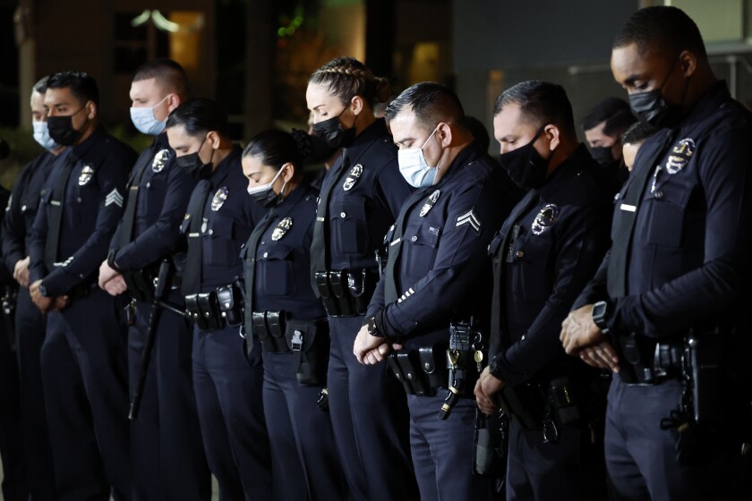 LOSA ANGELES, CA - JANUARY 12, 2022: Los Angeles Police Officers bow their heads in prayer to honor their fallen LAPD Officer Fernando Arroyos, who was shot an killed during an armed robbery attempt Monday, outside the Olympic Community Police Station on January 12, 2022 in Los Angeles, California.(Gina Ferazzi / Los Angeles Times)