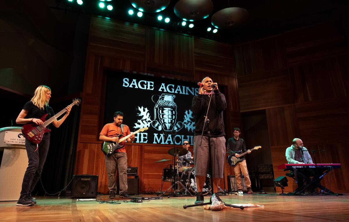 Six punk rock musicians onstage with frontman Antonio Sanchez singing in front, and his bandmates behind him. 