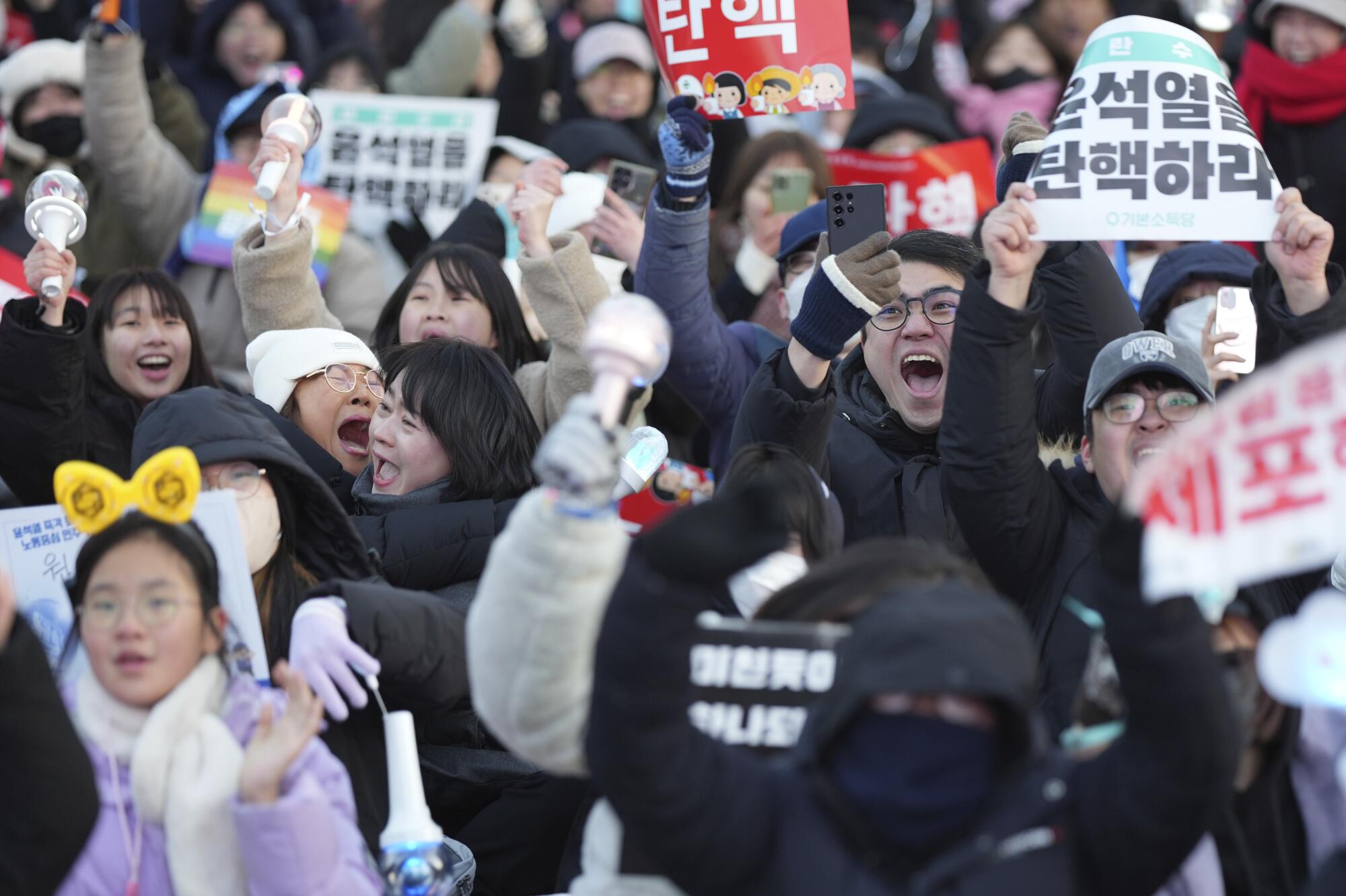 People in Seoul celebrate after hearing the news that South Korea's parliament voted to impeach President Yoon Suk Yeol.