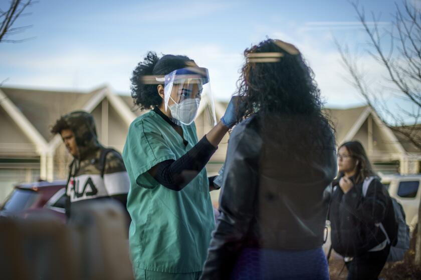 FILE - Maya Goode, a COVID-19 technician, performs a test on Jessica Sanchez outside Asthenis Pharmacy in Providence, R.I., Dec. 7, 2021. Scientists are seeing signals that COVID-19′s alarming omicron wave may have peaked in Britain and is about to do the same in the U.S., at which point cases may start dropping off dramatically. (AP Photo/David Goldman, File)