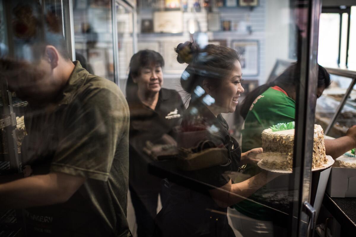 Melissa Chan. center, serves a customer at Phoenix Bakery in Chinatown. Her father, Youlen Chan, now runs the business.