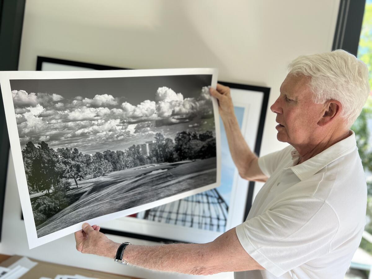 John Light holds up a black-and-white photograph he took of the 16th hole at Los Angeles Country Club.