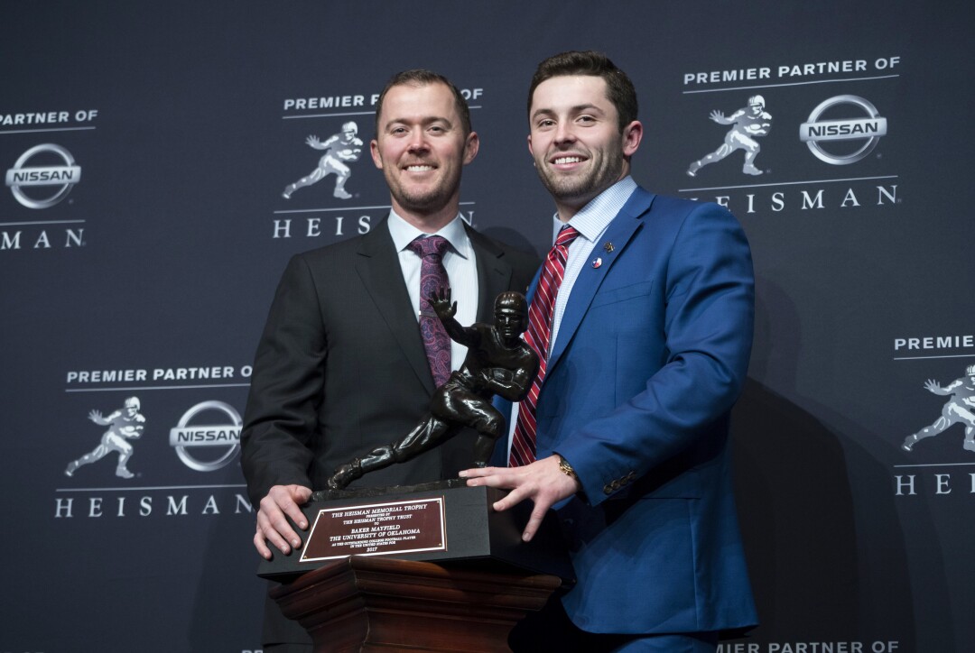 Oklahoma coach Lincoln Riley stands with Sooners quarterback Baker Mayfield next to the Heisman Trophy