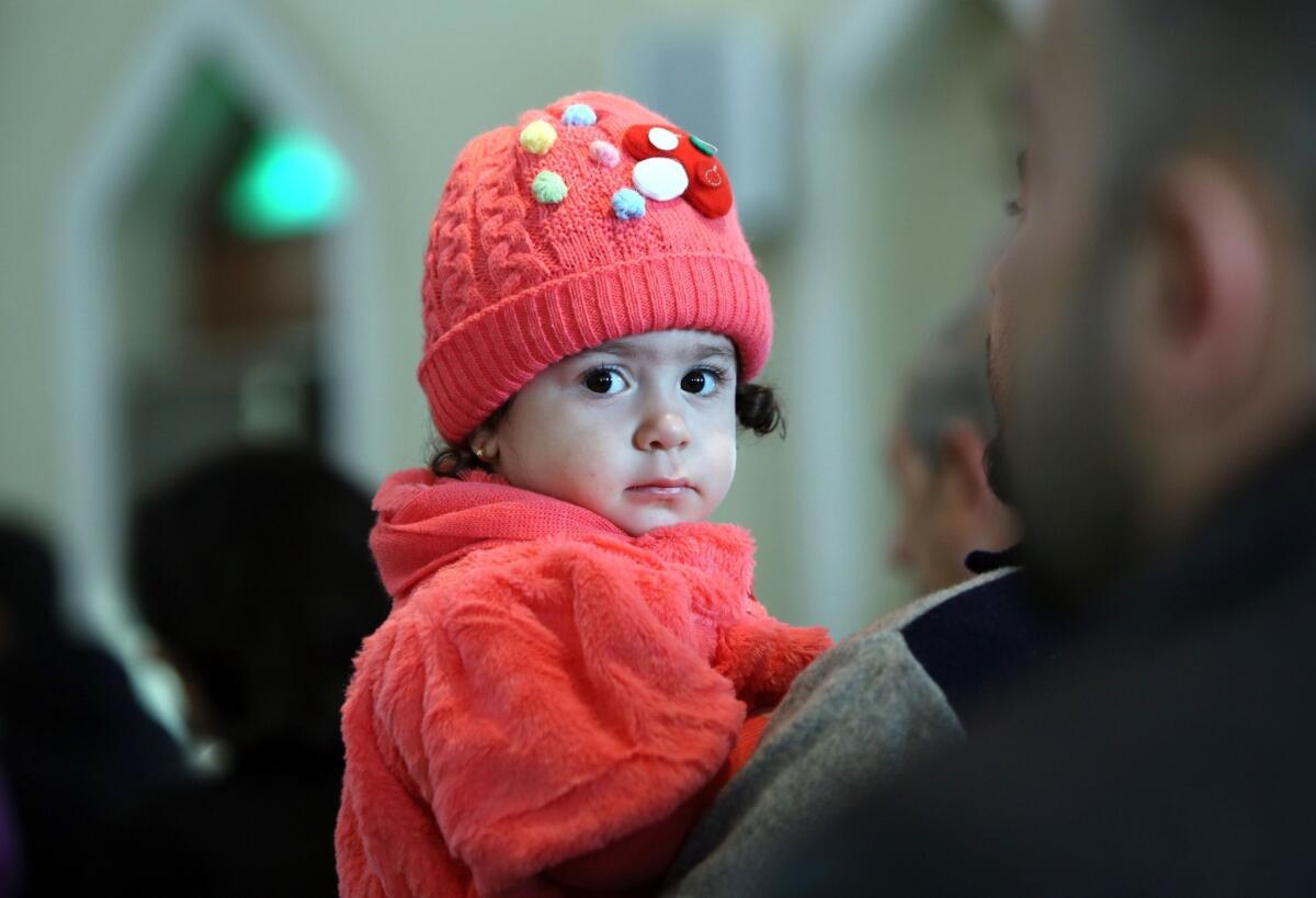 An Iraqi Christian child sits in her father's arms as she attends a Christmas service at the Church of Our Lady of Sacred Heart in the Karrada neighborhood of Baghdad on Wednesday.