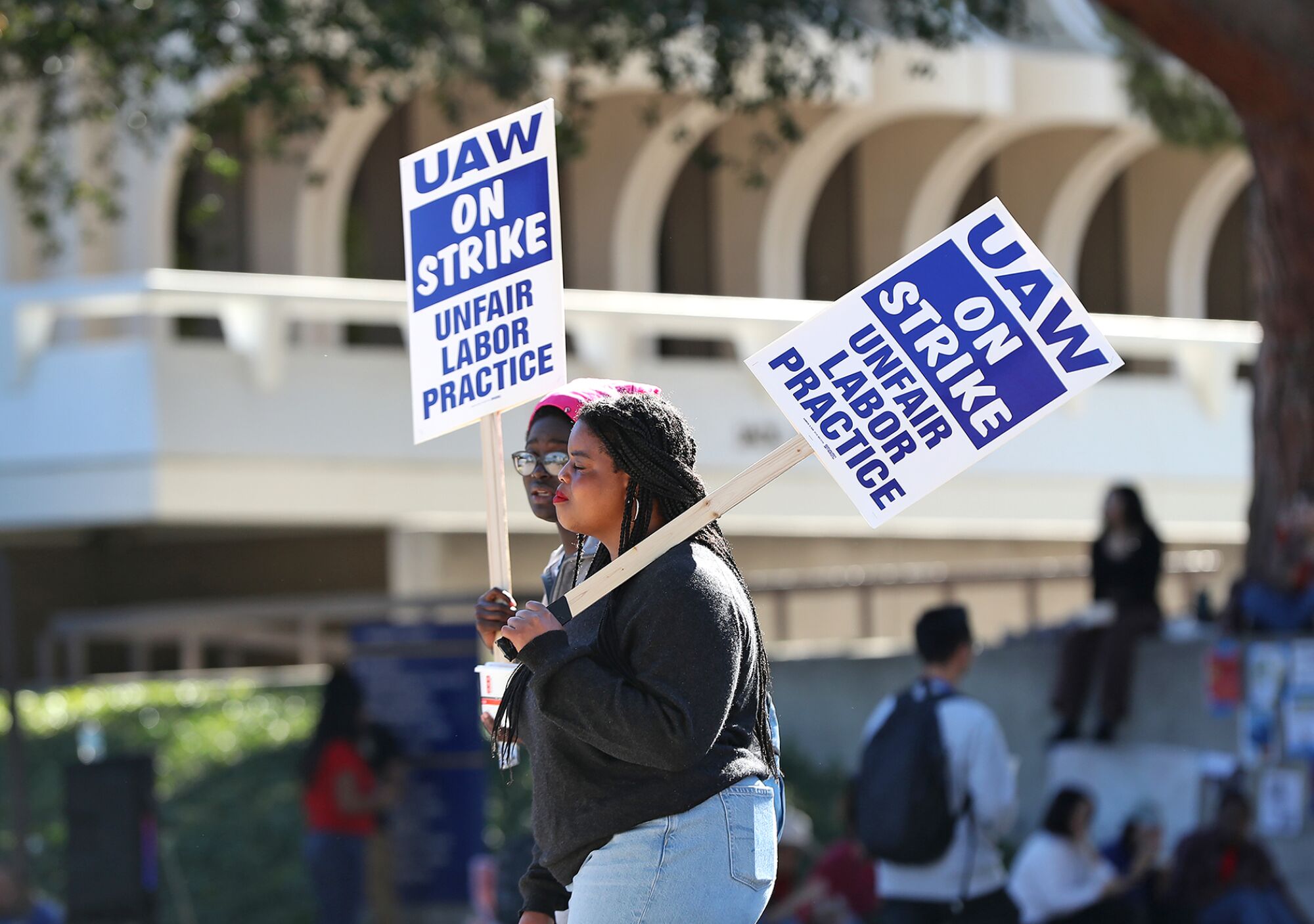 Two students are seen in profile while they walk with picket signs on Monday on US Irvine campus. 