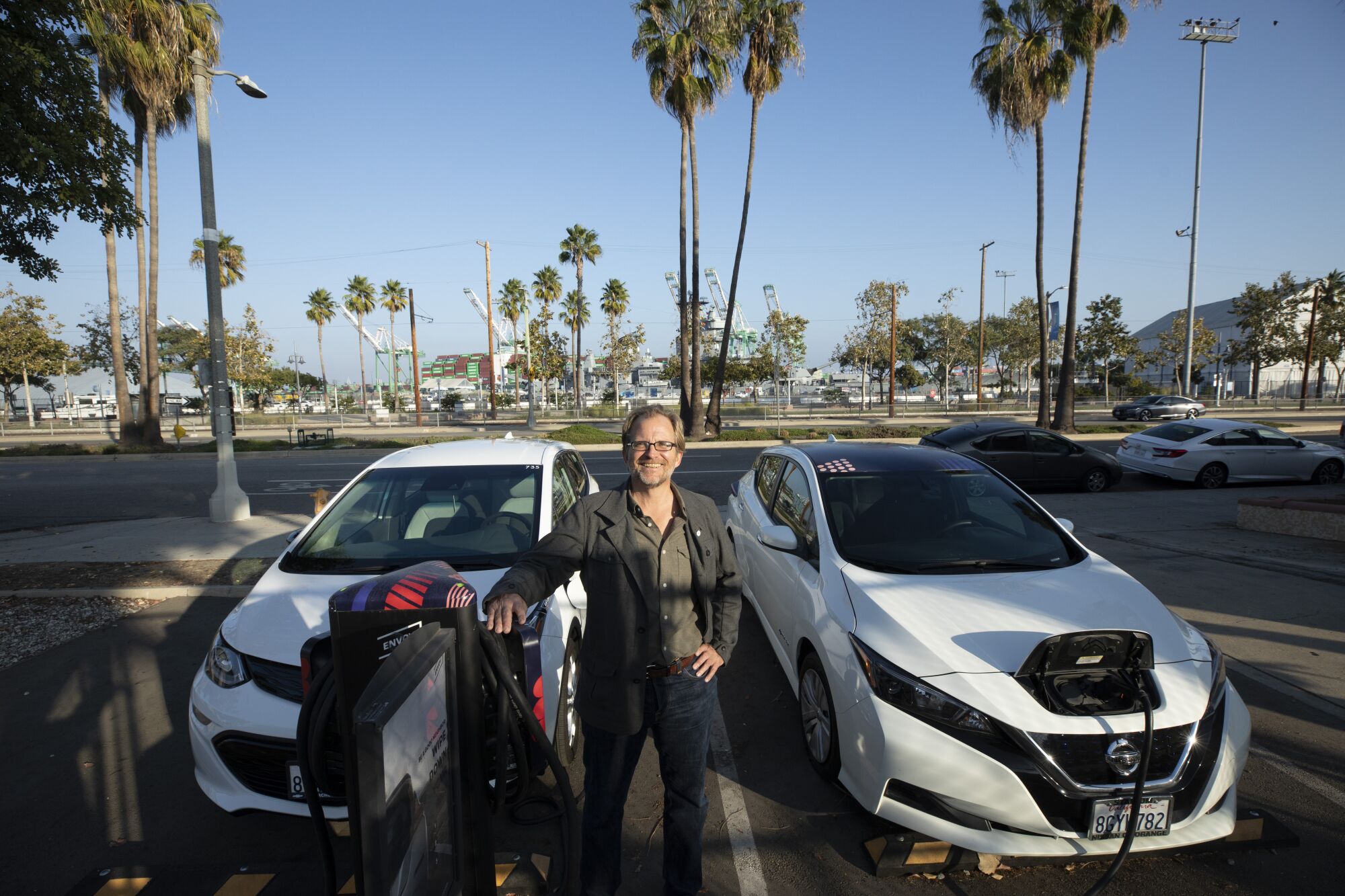Matt Petersen stands between two cars plugged in at an electric charging station near the Port of Los Angeles.
