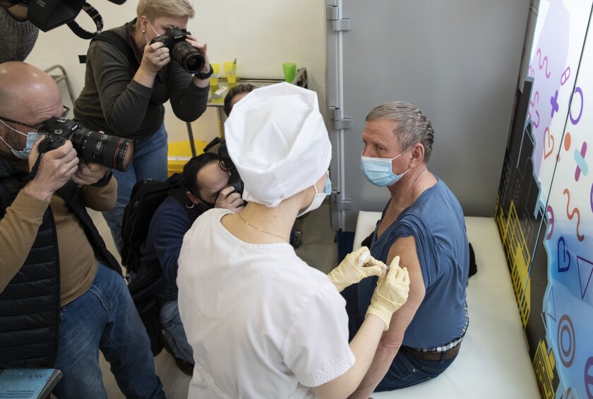 News photographers take pictures as a medical worker administers a shot of Russia's Sputnik V coronavirus vaccine in Moscow, Russia, Wednesday, April 7, 2021. Germany’s health minister Jens Spahn said Thursday April 8, 2021, the European Union doesn’t plan to order Russia’s Sputnik V coronavirus vaccine but will hold separate talks with Russia. (AP Photo/Pavel Golovkin)