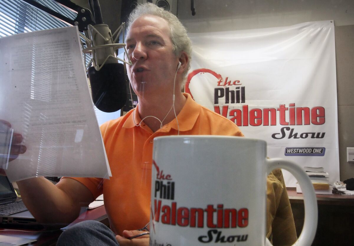 Phil Valentine in front of a microphone with a coffee cup and sign saying The Phil Valentine Show