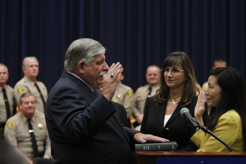 Sachi Hamai, right, then-executive officer to the Los Angeles Board of Supervisors, administers the oath of office to interim Sheriff John Scott on Jan. 30, 2014. Hamai is now the county's interim chief executive officer and Scott has been replaced by Sheriff Jim McDonnell.