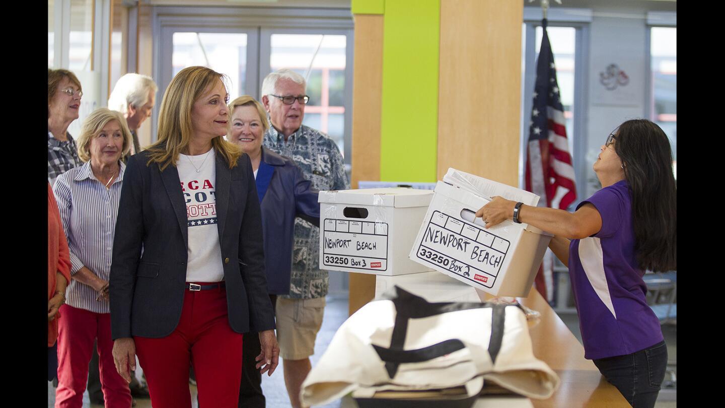 Lynn Swain, left, watches as Leilani Brown, the city clerk for Newport Beach, takes a box filled with petitions by people who want to recall Newport Beach City Councilman Scott Peotter at city hall on Friday, October 27.