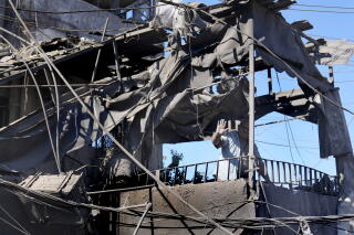 A man waves from his shattered house at the site of Israeli airstrikes in southern Beirut, Lebanon.