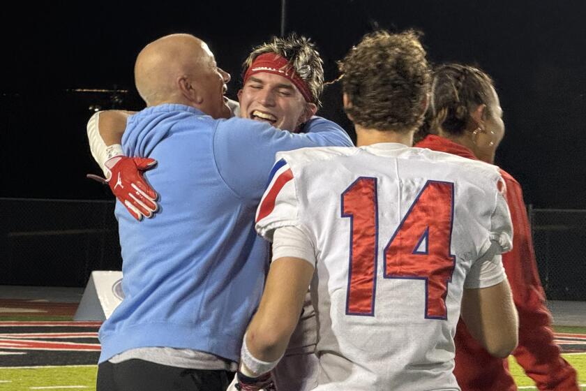 Los Alamitos coach Ray Fenton hugs defensive end Jackson Renger after 33-20 win over San Clemente in Division 2 final.