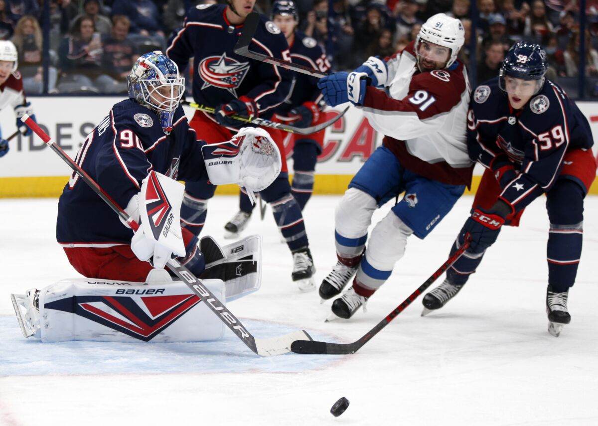 Columbus Blue Jackets goalie Elvis Merzlikins, left, stops a shot in front of Colorado Avalanche forward Nazem Kadri, center, and Blue Jackets forward Yegor Chinakhov during the first period of an NHL hockey game in Columbus, Ohio, Saturday, Nov. 6, 2021. (AP Photo/Paul Vernon)