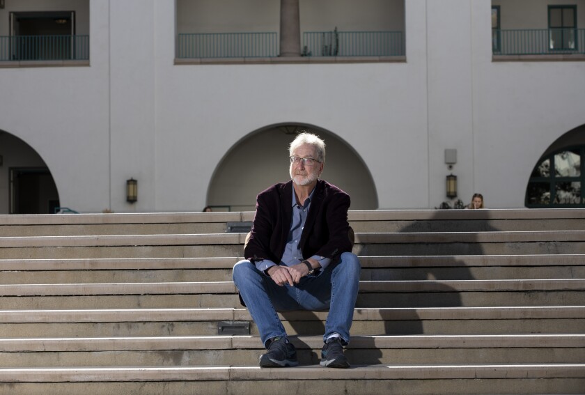 San Diego State professor Peter Herman sits on steps outdoors.
