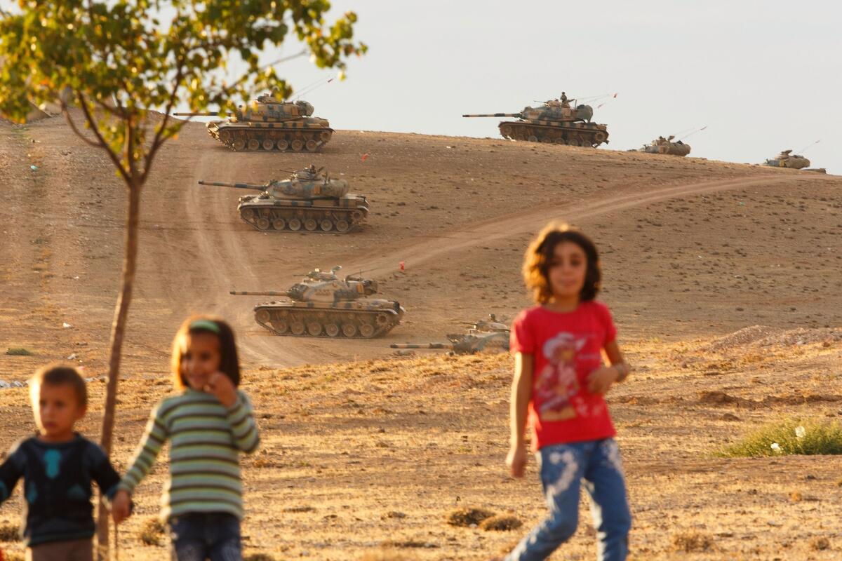 Children run in Sanliurfa, Turkey, while tanks from the Turkish armed forces are dispatched to the Turkish-Syrian border as clashes intensified with Islamic State militants on Monday.