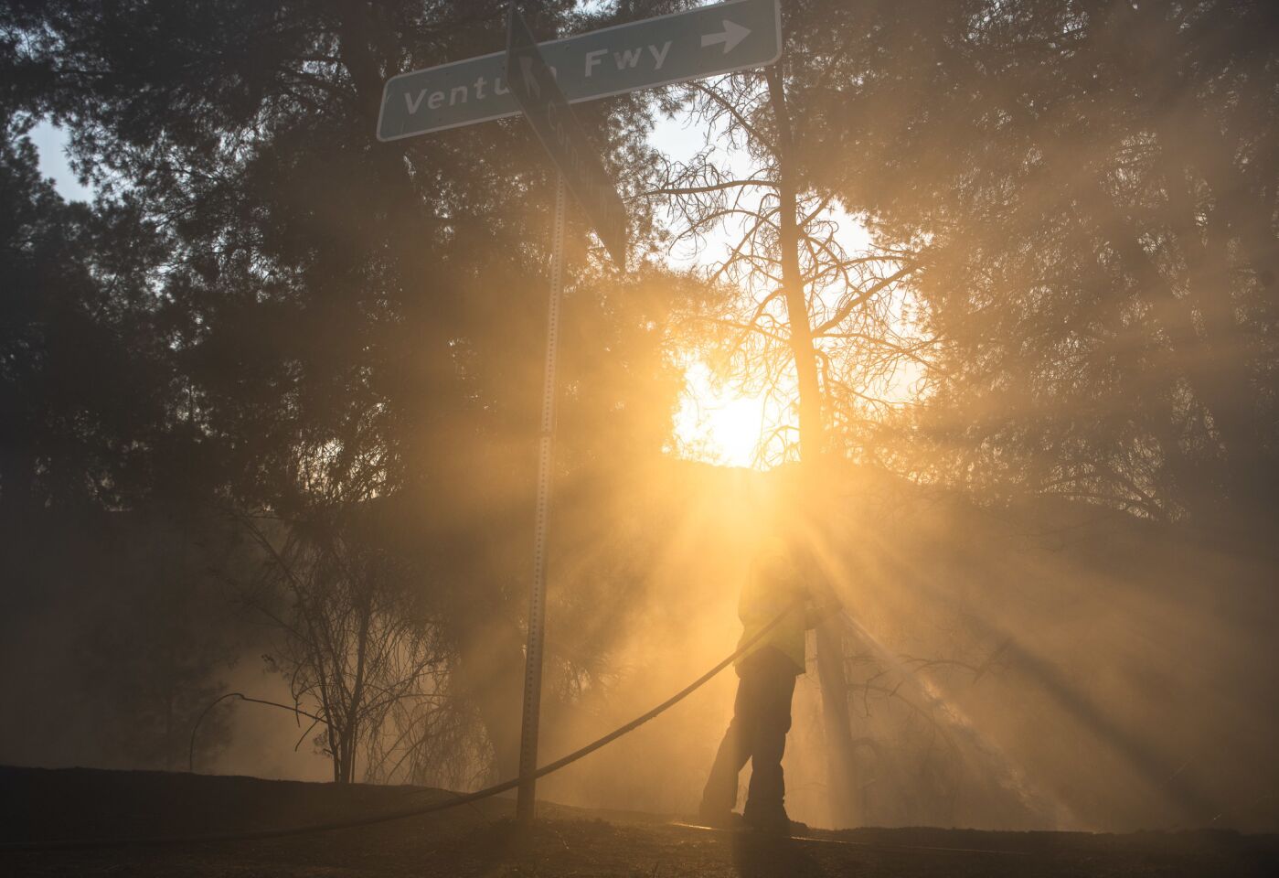 A Southern California Edison employee hoses down a hot spot off Kanan Road on Nov. 10. The crew was checking for hot spots around power lines.