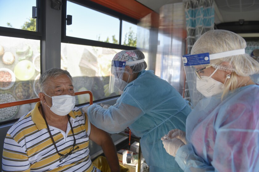 ARCHIVO - En esta imagen del 4 de septiembre de 2021, un hombre recibe una vacuna de Johnson & Johnson en un autobús empleado como centro móvil de vacunación en Bucarest, Rumanía. (AP Foto/Andreea Alexandru, Archivo)