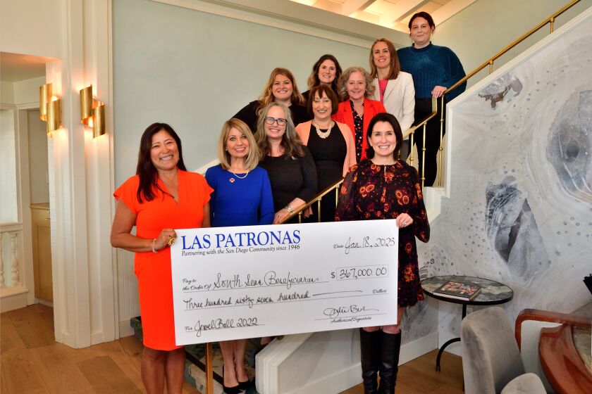Las Patronas members Mio Hood and Julie Bubnack hold a check representing the dollar amount given to its major beneficiaries.