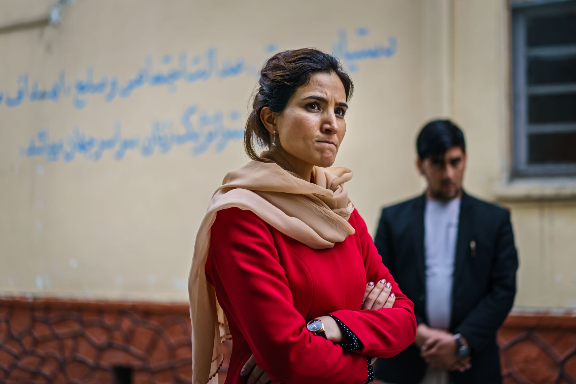 Hosna Jalil, arms folded, talks to staff members