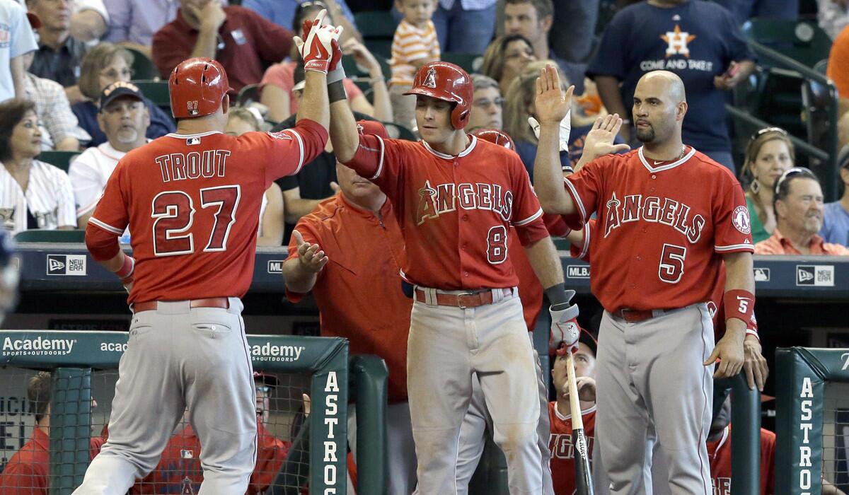 Angels Taylor Featherston (8) and Albert Pujols (5) welcome Mike Trout (27) back to the dugout after he scored on a David Freese two-run double against the Houston Astros on Wednesday.