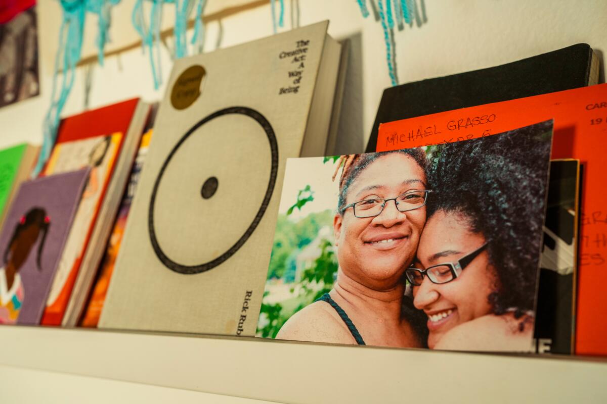 A photograph of Krysta Grasso and her mother on a shelf with books and art.