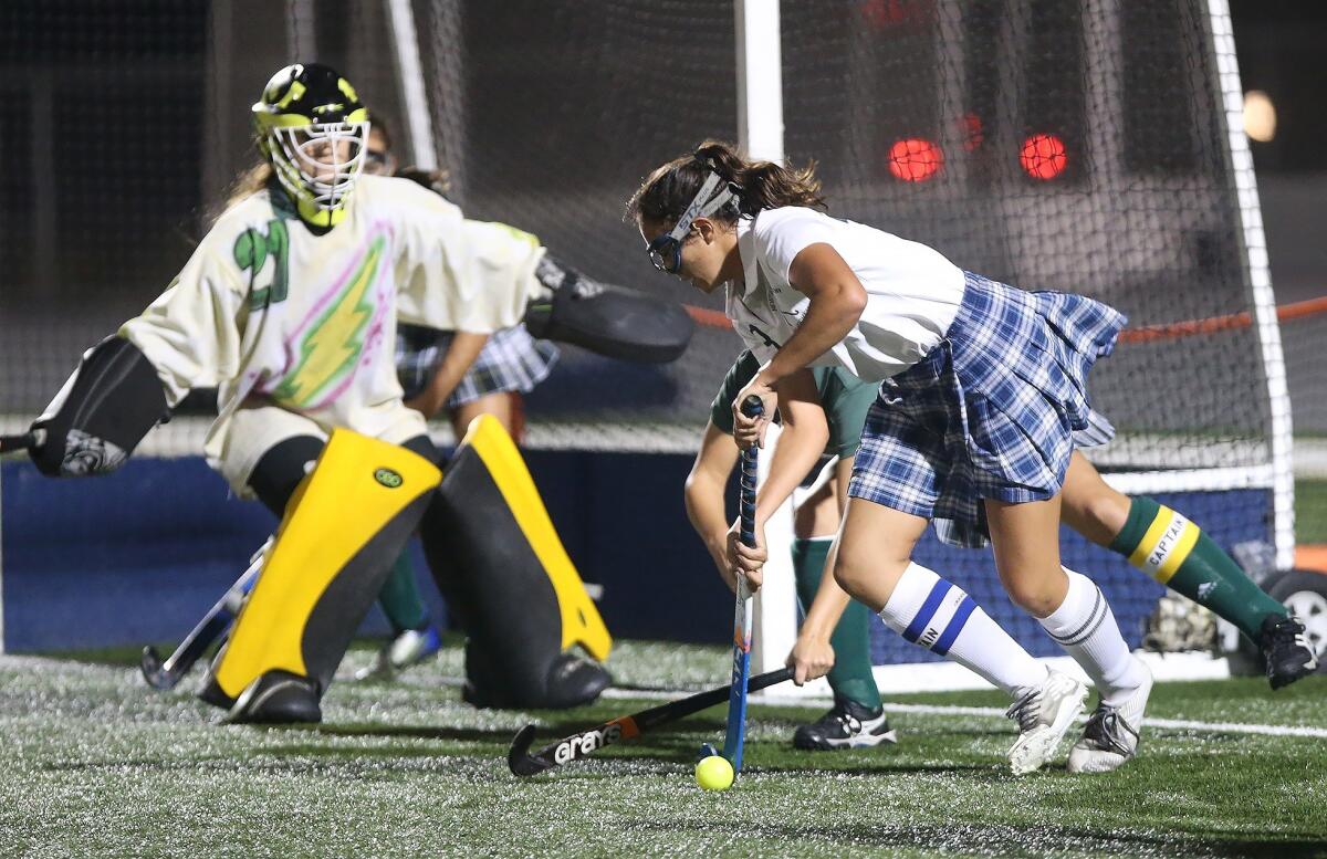 Newport Harbor High's Delaney Knipp, right, battles for position to get a shot off as Edison goalkeeper Mary Smith defends in a girls' field hockey game on Oct. 23, 2018.