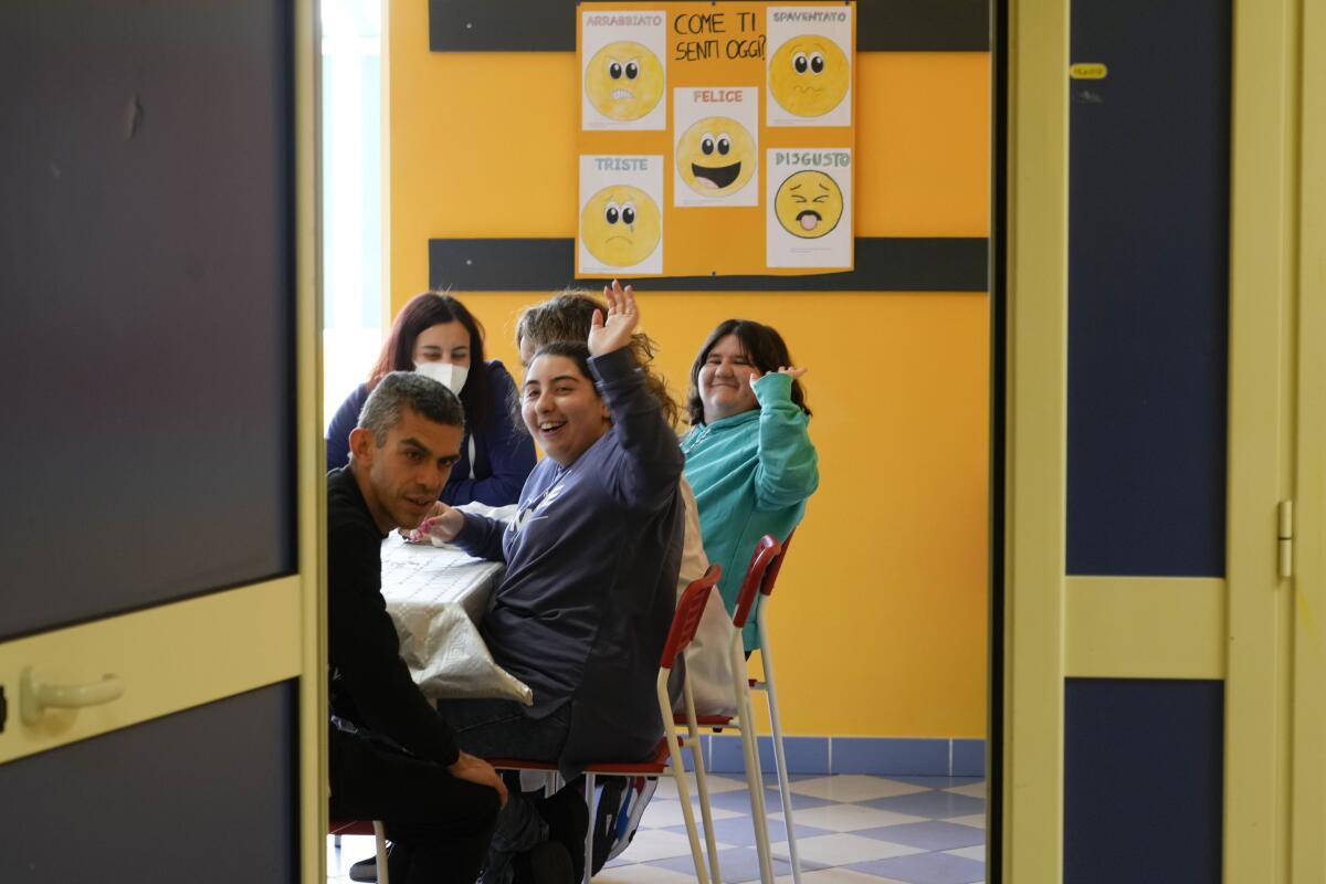 People wave to a photographer as they sit inside a facility of the Chicco community of L'Arche.