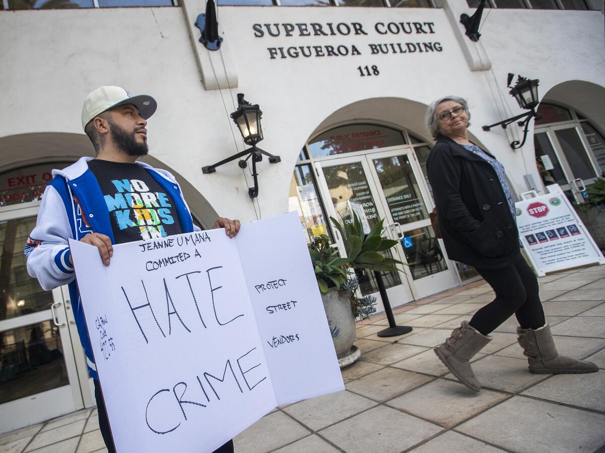 A man standing outside a courthouse with a sign with the words "hate crime"