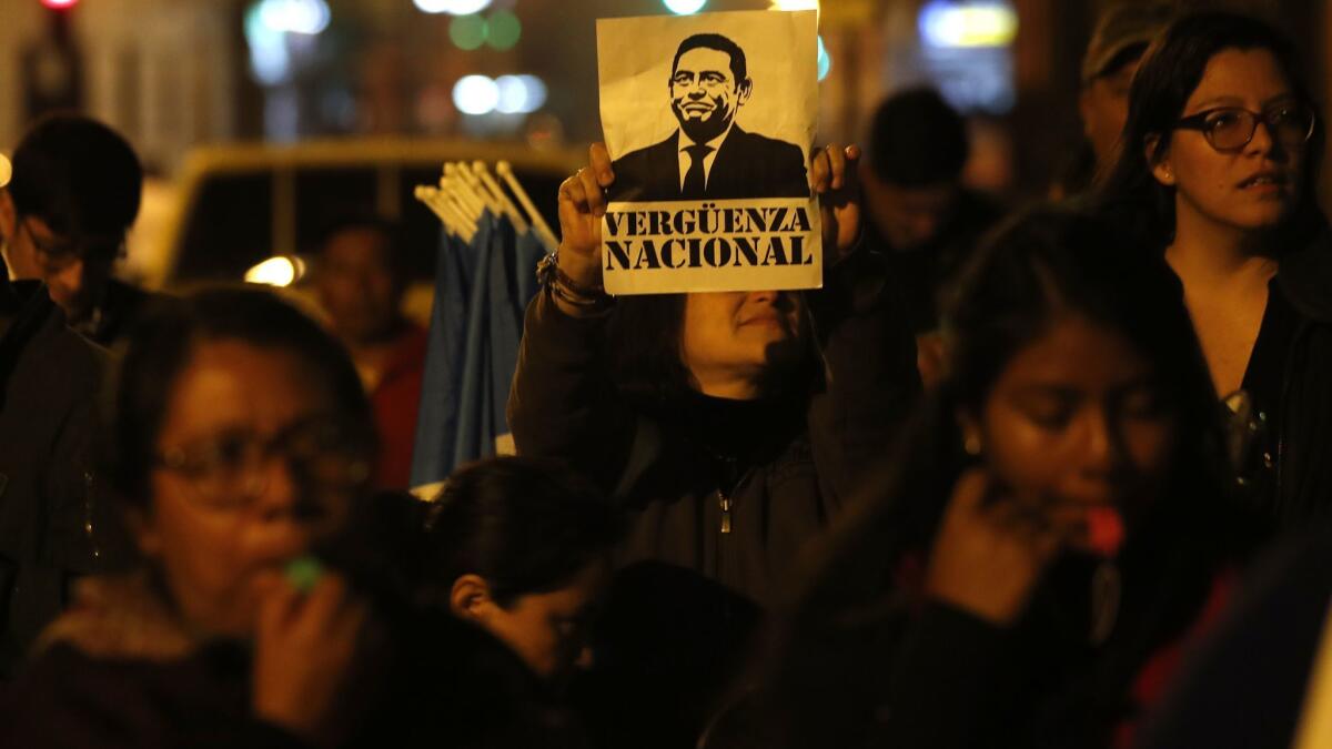 A woman holds up a sign with an image of Guatemalan President Jimmy Morales that reads "national shame" during a rally in support of the country's anti-corruption commission.