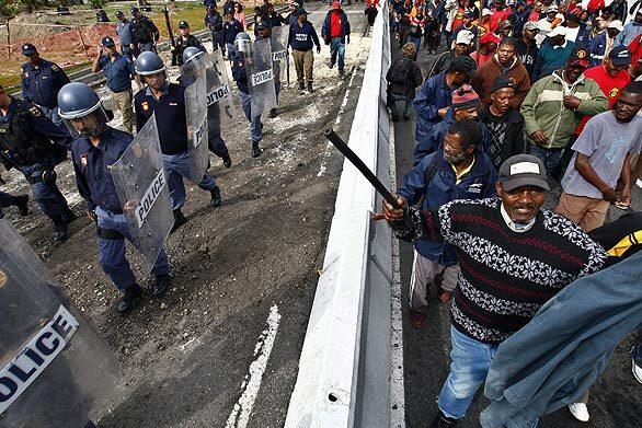 Striking South African municipal workers are monitored by police as they protest in Cape Town. Thousands of municipal workers across the country are into their third day of strikes following a breakdown in wage talks with the South African Local Government Assn.