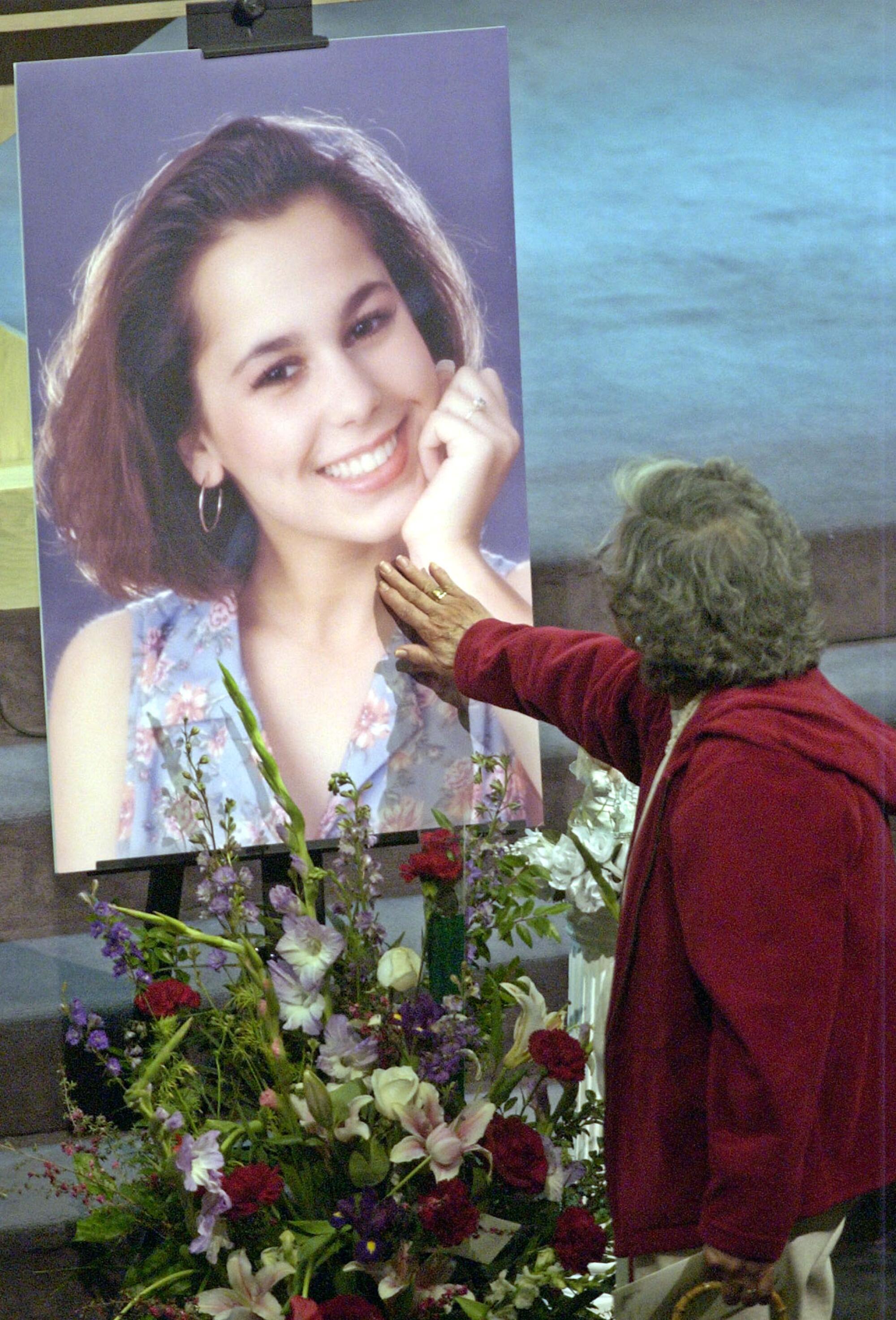 May 2003 photo of a mourner touching a picture of Laci Peterson during the memorial service in Modesto.